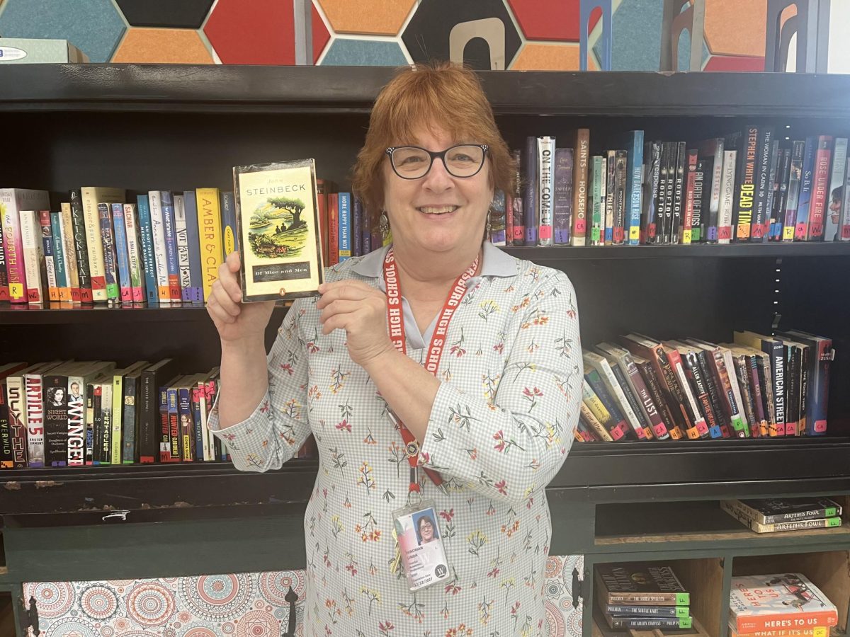 English teacher Linda Hindman with her favorite banned book, “Of Mice and Men”.