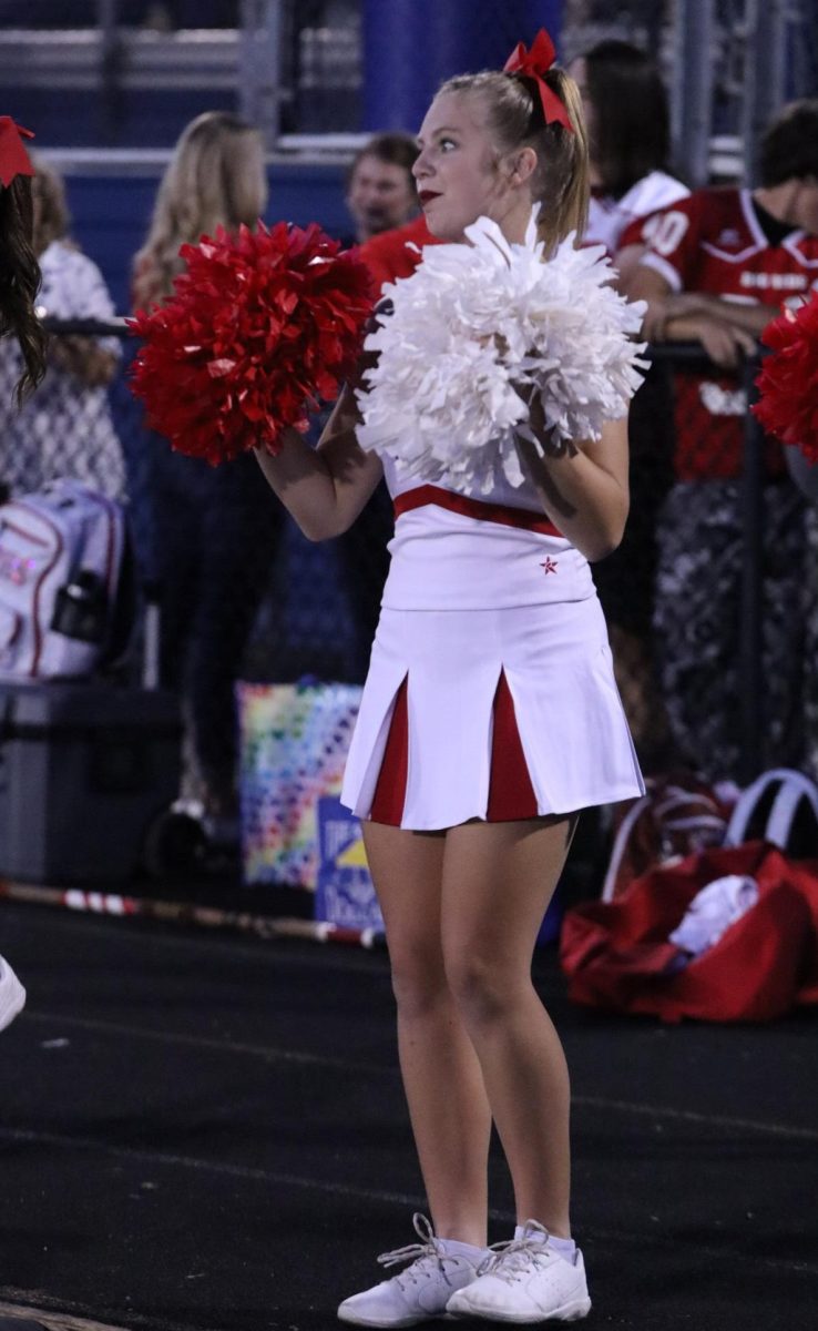 Freshman cheerleader Braley Cottrill performs a cheer on the sidelines.