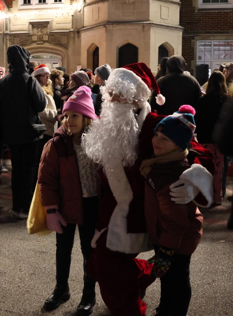 During the 2024 tree lighting, Santa poses with two children in front of the school.
