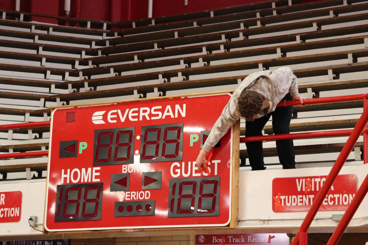 Junior Austin Craven puts tape over the S's on the scoreboard in the visitor student section in the Fieldhouse Jan. 5.