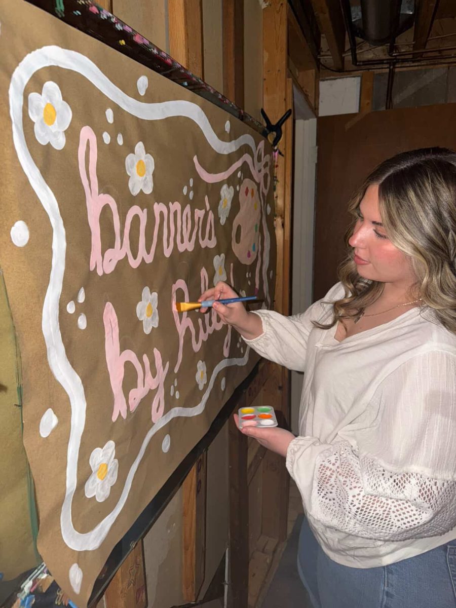 Junior Riley Ball paints a banner to promote her business Feb 16. 