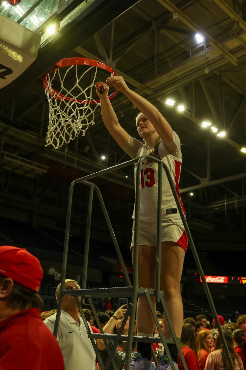 Senior Lucie Cline cuts down part of the championship net March 14. 
