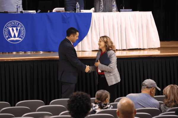 Sports in American History teacher Sam Vincent shakes hands with Superintendent Christie Willis after being announced the 2027 Wood County Teacher of the Year during the Board of Education meeting in the auditorium April 28. 