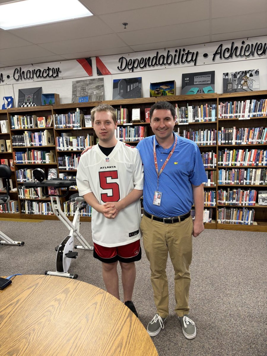 Senior Jacob Smith and sports history teacher Sam Vincent in the library April 14 after Smith was surprised with an invitation to announce an Atlanta Falcons draft pick at the NFL Draft.